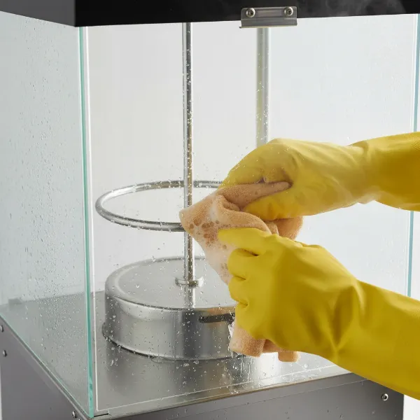 Hand cleaning a popcorn maker stirring rod with a soapy cloth after use.